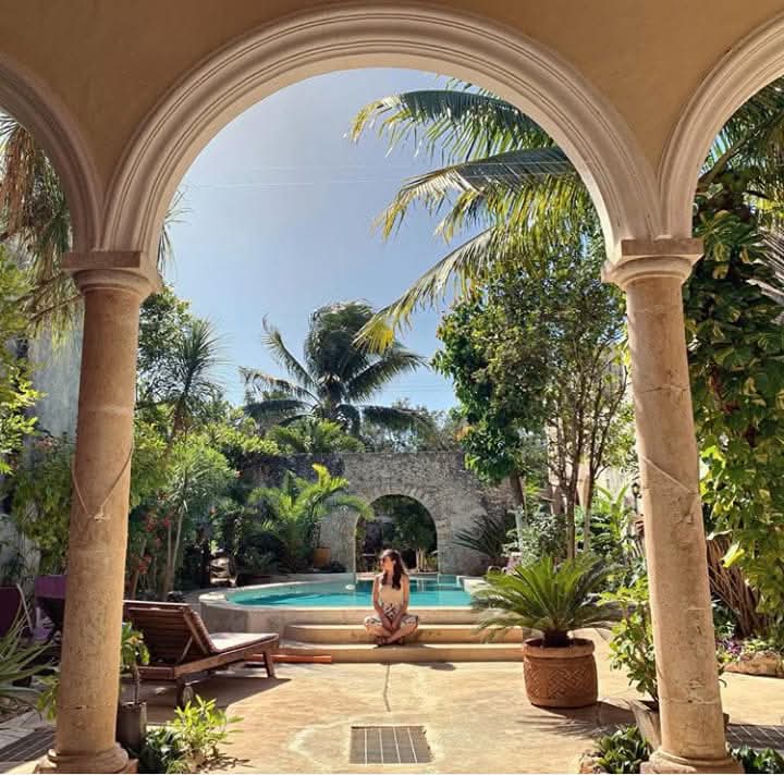 Stone arches framing a lush courtyard and swimming pool
